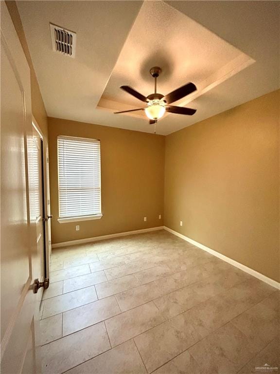 tiled spare room with a textured ceiling, a tray ceiling, and ceiling fan