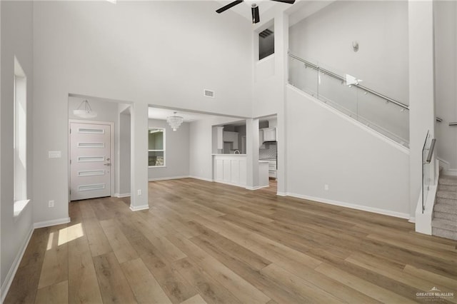 6300 Cascada Bend Rd, Mcallen, TX 78504 - unfurnished living room with ceiling fan, stairway, light wood-style floors, and a towering ceiling