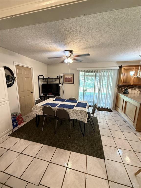 dining space with light tile patterned floors, ceiling fan, and a textured ceiling