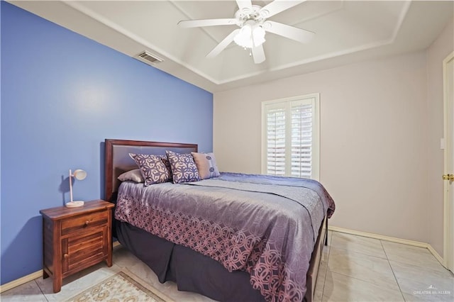 tiled bedroom featuring ceiling fan and a tray ceiling