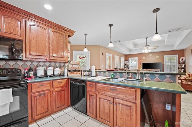 kitchen featuring sink, light tile patterned floors, backsplash, a tray ceiling, and black appliances