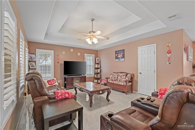 tiled living room featuring ceiling fan and a raised ceiling