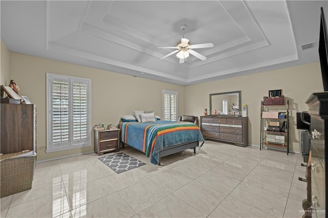 bedroom with multiple windows, a raised ceiling, and ceiling fan