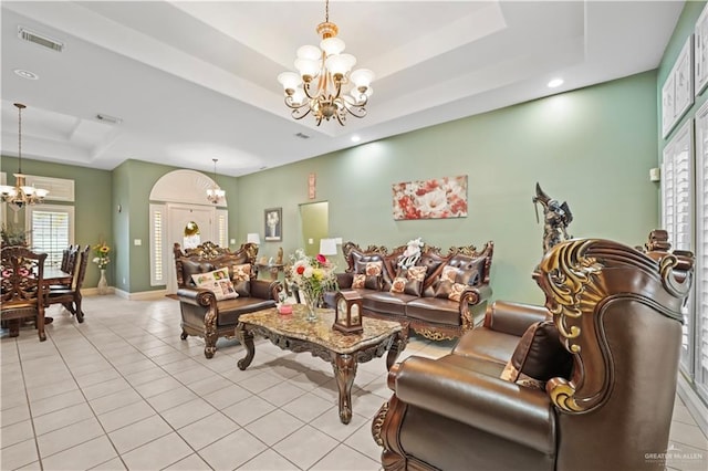 living room featuring a raised ceiling, light tile patterned floors, and a chandelier