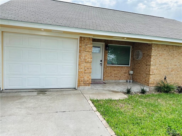 1523 Evergreen Ave, Mission, TX 78572 - doorway to property with concrete driveway, brick siding, a shingled roof, a yard, and an attached garage