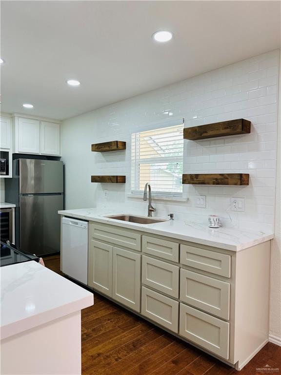 1523 Evergreen Ave, Mission, TX 78572 - kitchen with open shelves, white dishwasher, freestanding refrigerator, dark wood-style flooring, and light countertops