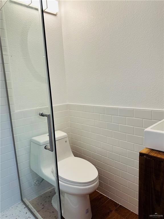 1523 Evergreen Ave, Mission, TX 78572 - bathroom featuring tile walls, a wainscoted wall, wood finished floors, vanity, and a stall shower