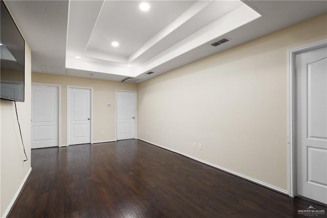 interior space with dark hardwood / wood-style floors and a raised ceiling