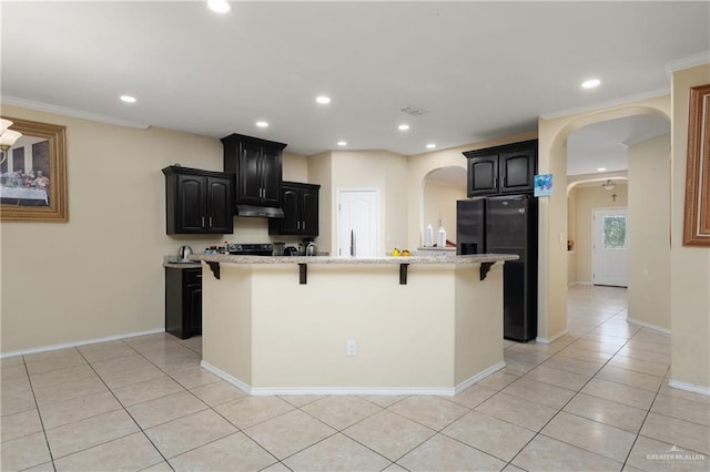 kitchen with black fridge, a kitchen island with sink, and ornamental molding