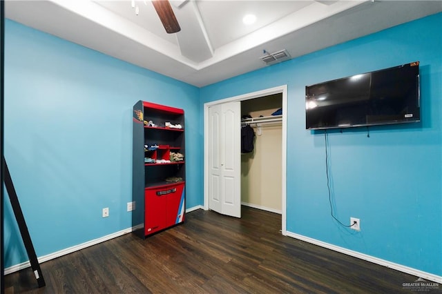 unfurnished bedroom with ceiling fan, a closet, and dark wood-type flooring