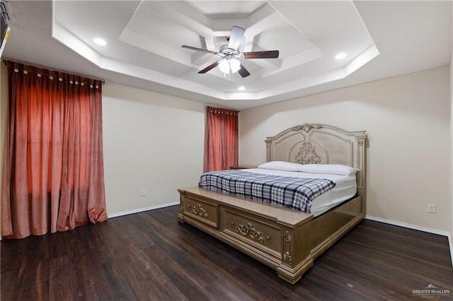 bedroom with a raised ceiling, ceiling fan, and dark wood-type flooring