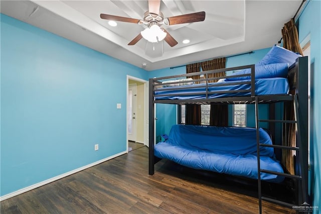 bedroom featuring a raised ceiling, ceiling fan, and dark hardwood / wood-style flooring