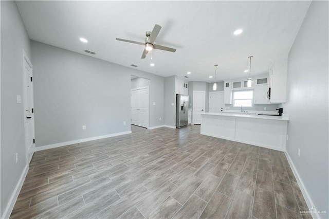 unfurnished living room featuring ceiling fan, light wood finished floors, recessed lighting, and baseboards