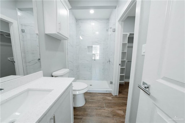 2605 Sage Dr, Weslaco, TX 78596 - full bathroom with a marble finish shower, toilet, vanity, a walk in closet, and wood finish floors