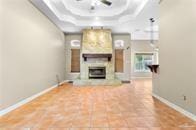 unfurnished living room with a tray ceiling, baseboards, and a fireplace