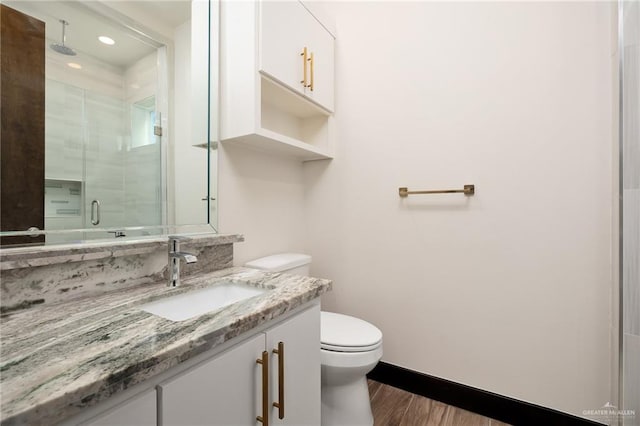 bathroom featuring vanity, wood-type flooring, an enclosed shower, and toilet