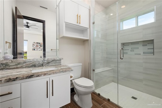 bathroom featuring hardwood / wood-style floors, vanity, ceiling fan, toilet, and walk in shower