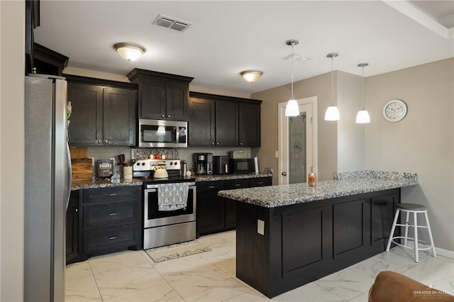 kitchen with light stone countertops, appliances with stainless steel finishes, kitchen peninsula, and hanging light fixtures