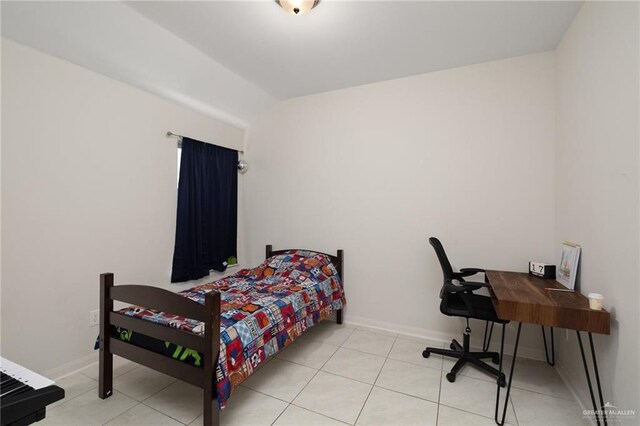 bedroom with lofted ceiling, light tile patterned floors, and baseboards