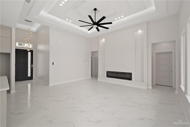 unfurnished living room with a raised ceiling, marble finish floor, baseboards, and ceiling fan with notable chandelier