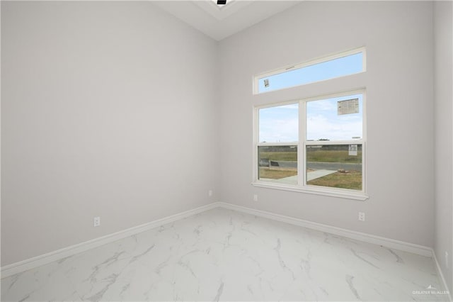 spare room featuring marble finish floor and baseboards