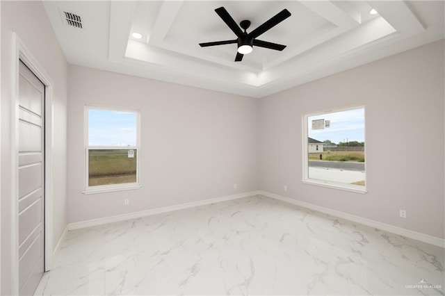 spare room featuring a tray ceiling, visible vents, marble finish floor, and a healthy amount of sunlight