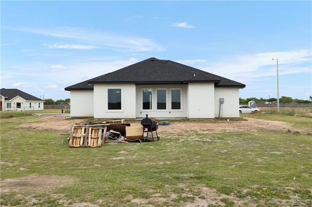 rear view of property with a lawn, roof with shingles, and stucco siding