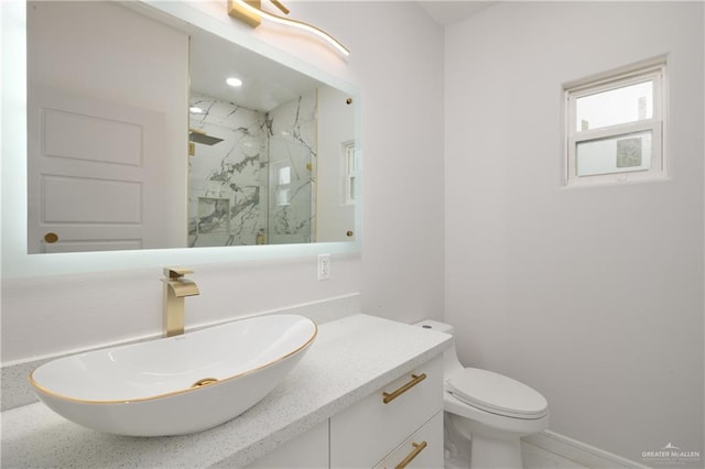 bathroom with baseboards, a marble finish shower, vanity, and toilet