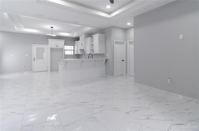 unfurnished living room featuring a tray ceiling and sink