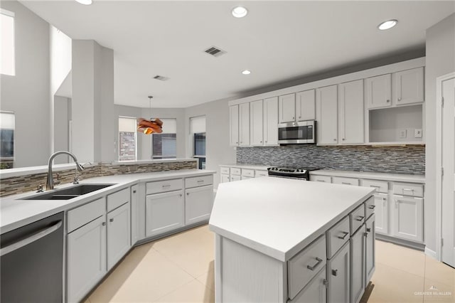 kitchen with a center island, hanging light fixtures, sink, appliances with stainless steel finishes, and tasteful backsplash