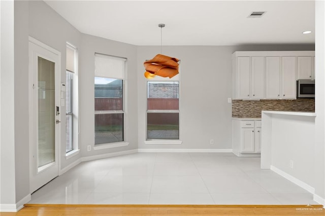 unfurnished dining area featuring light tile patterned floors and plenty of natural light