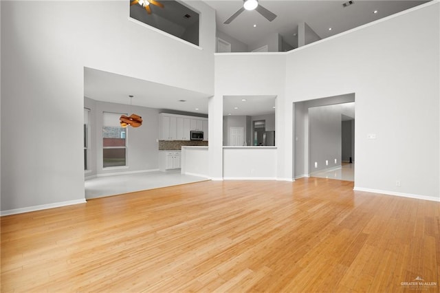 unfurnished living room with ceiling fan, light hardwood / wood-style flooring, and high vaulted ceiling