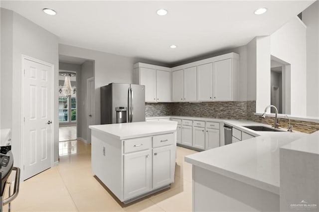 kitchen with white cabinetry, sink, stainless steel appliances, decorative backsplash, and a kitchen island