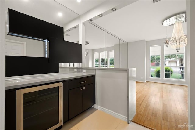 kitchen featuring a chandelier, light hardwood / wood-style floors, beverage cooler, and a healthy amount of sunlight