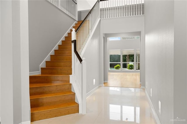 stairway with tile patterned flooring and a towering ceiling