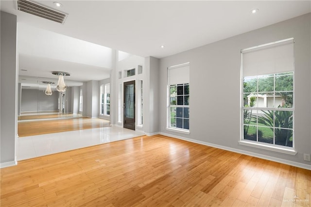 interior space with a healthy amount of sunlight, light hardwood / wood-style floors, and an inviting chandelier