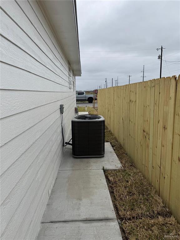 view of property exterior with fence, a patio, and central AC unit