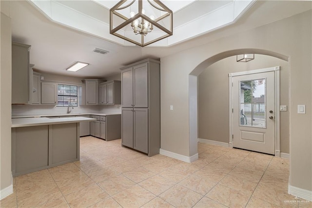 kitchen with decorative light fixtures, gray cabinets, a notable chandelier, and sink