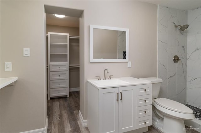 bathroom with tiled shower, vanity, hardwood / wood-style flooring, and toilet