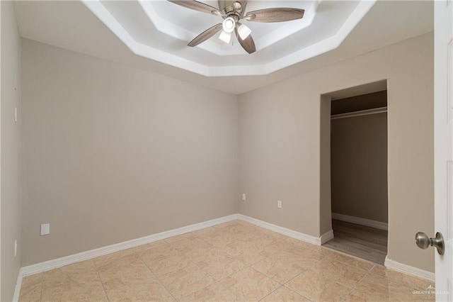 unfurnished bedroom with light tile patterned floors, a closet, a raised ceiling, and ceiling fan