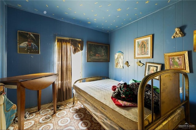 bedroom featuring crown molding and wood walls