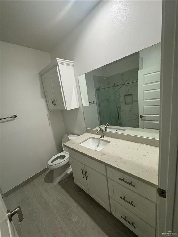 bathroom featuring vanity, toilet, wood-type flooring, and walk in shower