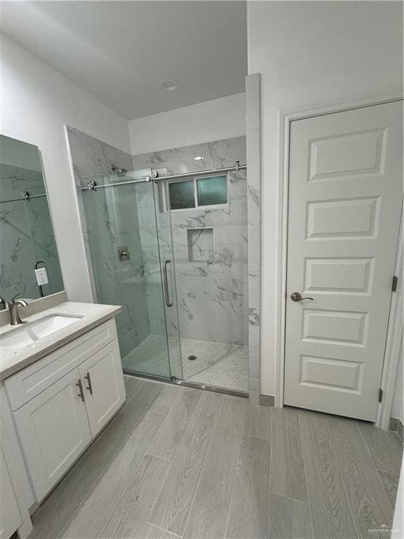 bathroom with hardwood / wood-style floors, vanity, and walk in shower