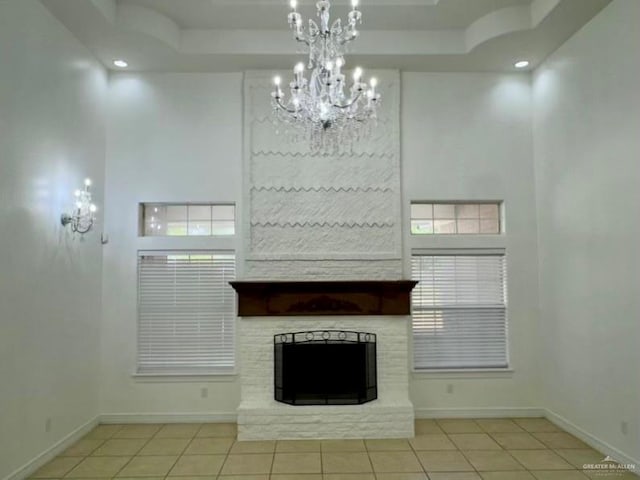 unfurnished living room with a notable chandelier, a stone fireplace, light tile patterned floors, and a high ceiling