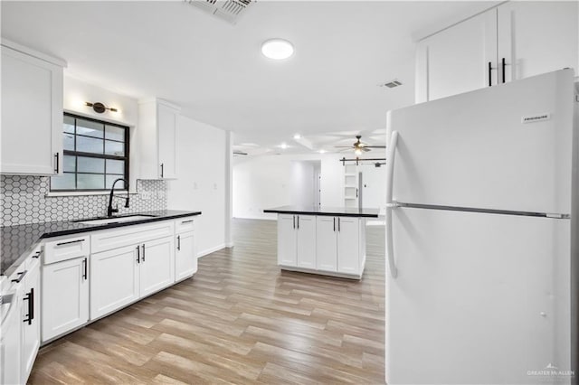 kitchen with backsplash, sink, light hardwood / wood-style flooring, white cabinets, and white fridge