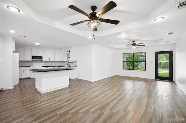 kitchen featuring white appliances, a tray ceiling, ceiling fan, light hardwood / wood-style flooring, and white cabinetry