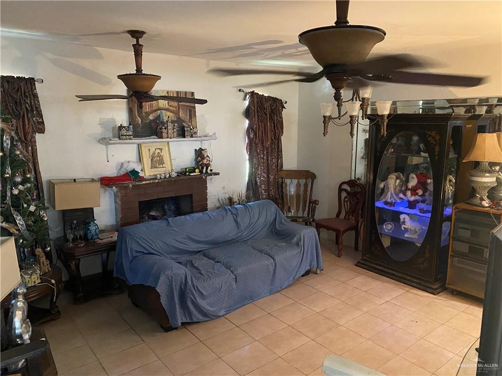 living area with light tile patterned floors, a fireplace, and a ceiling fan