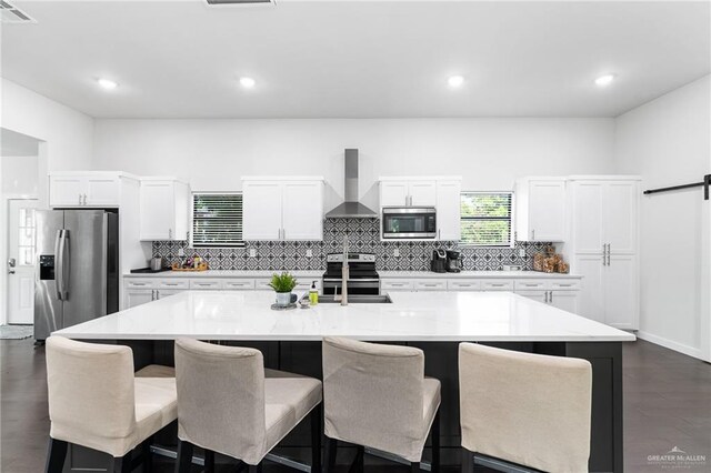 136 W Evergreen St, Boerne, TX 78006 - kitchen with wall chimney range hood, appliances with stainless steel finishes, backsplash, a kitchen bar, and recessed lighting