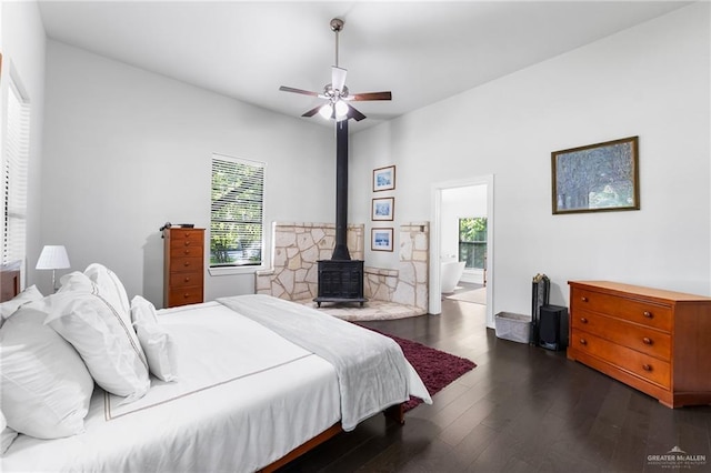 136 W Evergreen St, Boerne, TX 78006 - bedroom featuring a wood stove, dark wood finished floors, ceiling fan, and ensuite bathroom