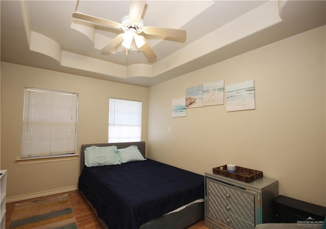 bedroom featuring a tray ceiling, ceiling fan, and dark hardwood / wood-style flooring